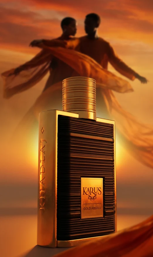 Close-up of Karus Gold Absolu bottle with subtle praline pieces and vetiver roots positioned strictly on the left and right sides of the glass.